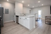 This well-appointed single-floor residence offers a clean, modern aesthetic with thoughtful design throughout. The open-concept layout connects the kitchen and living area seamlessly, creating a spacious and functional common area. The kitchen is fully equipped with stainless steel appliances — including a refrigerator, range, microwave, and dishwasher — paired with white cabinetry, marble-style countertops, a double basin sink, and a peninsula with bar seating, ideal for casual dining. Light wood-style flooring runs through the main living spaces, enhancing the bright and airy feel. The living area provides ample room for relaxing or entertaining, with access to a exterior door that brings in natural light. The residence includes multiple bedrooms, each carpeted for comfort, with windows that allow generous natural light and views of the surrounding area. Sliding mirrored closet doors feature in several bedrooms, adding both storage and visual depth. Two full bathrooms are finished consistently with marble-style vanity countertops, white cabinetry, and tub-shower combinations with brushed nickel fixtures. Recessed lighting throughout the home ensures a well-lit environment in every room. Overall, the space presents a cohesive, contemporary interior that is move-in ready.