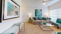 Located at 1400 El Camino Village Dr in Houston, TX, this thoughtfully designed single-floor residence offers a comfortable and functional layout across a well-connected set of living spaces. The open living room serves as the heart of the home, featuring plush carpeting, crown molding, a ceiling fan, and generous natural light from large windows with blinds. The space flows seamlessly into a breakfast bar area, creating an inviting hub for relaxing and entertaining. The kitchen is efficiently laid out with warm wood-toned cabinetry, white appliances including a range and built-in microwave, and rich hardwood-style flooring that extends throughout the wet areas. A separate dining nook with a pendant light fixture and window provides a defined space for meals. The bedroom is generously sized with carpeted floors, crown molding, and a large window that fills the room with natural light. It includes direct access to a walk-in closet with built-in shelving and a dedicated in-unit laundry room equipped with a full-size washer and dryer. The bathroom features a dual-sink vanity with white countertops, a large mirror, recessed lighting, and a soaking tub with shower. Throughout, the residence maintains a clean, neutral palette complemented by hardwood-style and carpeted flooring.