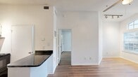 This 480 square foot apartment offers a thoughtful layout maximizing space and functionality. The single-floor plan includes one bedroom (140 sq ft), one bathroom, and an open-concept kitchen and living area. Throughout the space, warm wood-tone flooring creates a cohesive look and adds warmth to the crisp white walls.

The living area boasts high ceilings and large windows, including an arched window, allowing abundant natural light to flood the space. Track lighting provides additional illumination options. The kitchen, while compact, is well-equipped with stainless steel appliances, including a full-size refrigerator and built-in microwave. White cabinetry contrasts nicely with dark countertops, and a unique lattice detail above the cabinets adds visual interest.

The bathroom features a shower/tub combination, a single vanity with a granite-look countertop, and ample storage. The bedroom, though modest in size, accommodates a queen-size bed and includes a ceiling fan for comfort. Additional amenities include a utility room and closet space for storage.

This apartment's efficient design and modern finishes make it an ideal choice for singles or couples seeking a contemporary urban living experience in a well-organized, low-maintenance space.