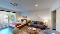 Situated at 301 E State Street in the heart of downtown Ithaca, New York, this modern studio offers a thoughtfully designed single-floor layout that maximizes both function and style. The open-concept main living area seamlessly integrates sleeping, lounging, and dining zones, finished with rich dark hardwood flooring and smooth white ceilings with recessed lighting and a ceiling-mounted HVAC unit. Large sliding glass doors flood the space with natural light and open onto a private balcony with views of the surrounding streetscape and greenery. A dedicated dining area with a wall-mounted flat-screen TV sits adjacent to the living space, enhancing versatility. A well-organized closet with built-in shelving provides ample storage. The galley-style kitchen features high-gloss white upper cabinetry, contrasting dark lower cabinets, quartz countertops, a white subway tile backsplash, a stainless steel undermount sink, and stainless steel appliances including a refrigerator and dishwasher. The bathroom is clean and contemporary, outfitted with large-format tile flooring, a floating white vanity with an illuminated mirror, and a walk-in shower. A stacked in-unit washer and dryer is conveniently tucked within the bathroom corridor, completing this efficient and modern urban residence.