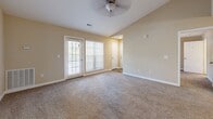 Located at 1825 Grove Point Rd in Savannah, Georgia, this single-floor residence offers a well-designed, functional layout with a warm, neutral color palette throughout. The open-concept living area features vaulted ceilings, a ceiling fan, and soft carpeting, flowing seamlessly into a kitchen highlighted by white cabinetry, granite countertops, stainless steel appliances — including a range, microwave, refrigerator, and dishwasher — and durable wood-look flooring. A breakfast bar provides a casual dining option at the kitchen's edge.

The space includes multiple bedrooms, each carpeted and equipped with ceiling fans and natural light from blinds-covered windows. The primary bedroom offers access to a walk-in closet, while additional bedrooms provide comfortable, versatile spaces. Sliding glass and French doors in several rooms connect to outdoor areas, enhancing the sense of openness and bringing in natural light. A dedicated laundry area houses a full-size washer and dryer with overhead shelving for added storage. The bathroom includes a full tub and shower combination. Throughout the home, consistent warm beige tones and clean white trim create a cohesive, inviting atmosphere.