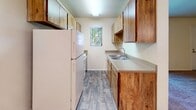 This single-floor residence is thoughtfully laid out to maximize functionality across its living spaces. The layout, as revealed by the 3D floor plan, connects a series of well-proportioned rooms with a logical flow from entry to living areas, kitchen, and bedrooms.

The living areas are finished with neutral-toned wall-to-wall carpeting, providing a warm and comfortable feel. Multiple windows fitted with horizontal blinds allow natural light to filter throughout, brightening the open, cream-painted walls. A ceiling fan is present in one of the main living areas, adding both circulation and ambient lighting.

The galley-style kitchen is efficiently designed with wood-toned cabinetry lining both walls, offering generous upper and lower storage. A double-basin sink, laminate countertops, and wood-look plank flooring complete the space. A window above the sink introduces additional natural light.

The bedrooms are generously sized, each featuring soft carpeting and multiple windows that invite natural light from multiple angles. One bedroom includes direct access to an exterior door, adding convenience.

The bathroom features a wide vanity with an extended countertop, undermount sink, and well-lit mirror, with wood-look flooring connecting seamlessly to the surrounding hallway.