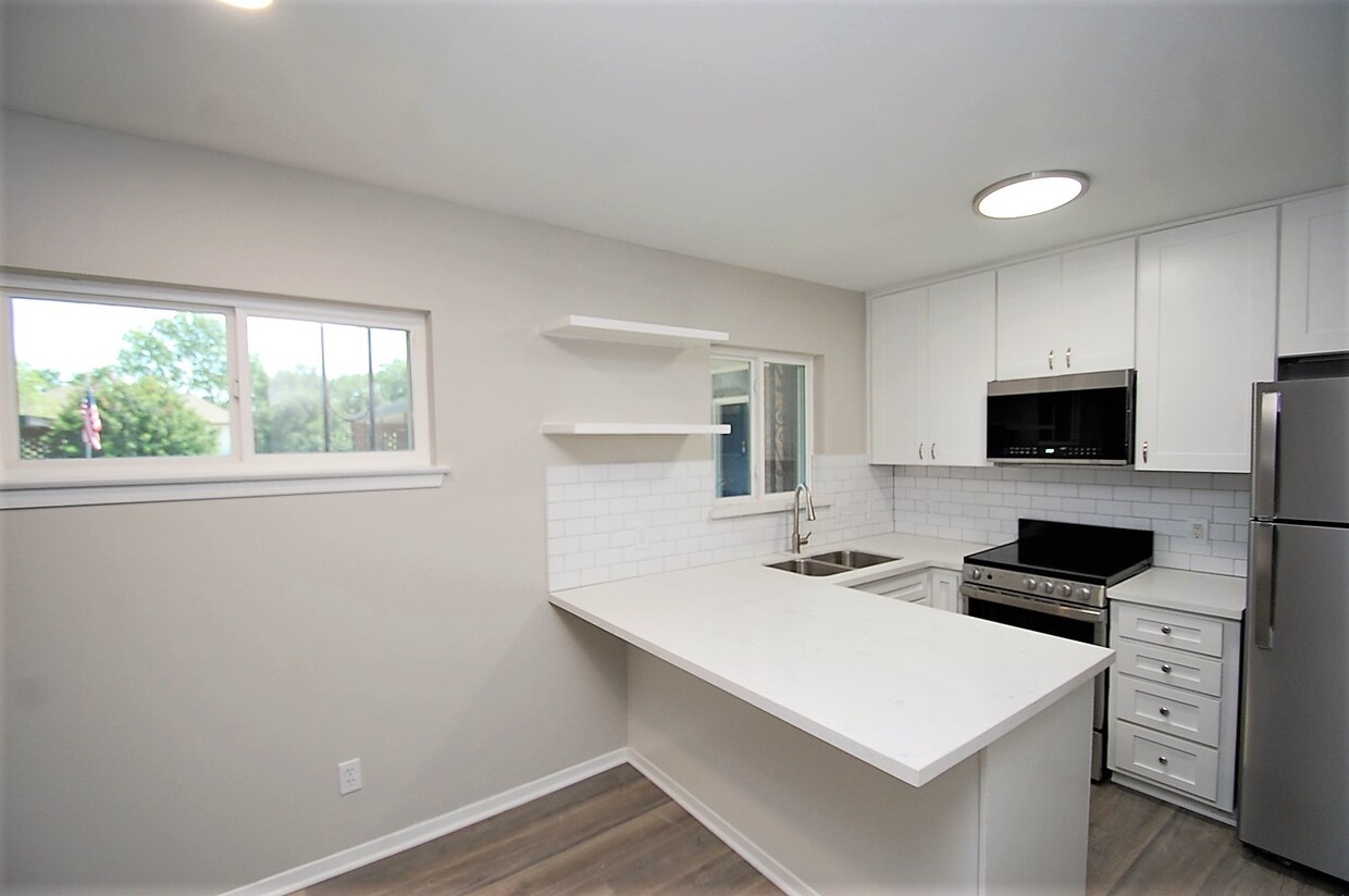 Kitchen with SS Appliances and Quartz Peninsula Countertops - Pine Village