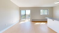 Located at 565 Talbot St in London, Ontario, this two-bedroom unit offers a thoughtfully laid-out single-floor plan with a clean, modern aesthetic throughout. Light wood laminate flooring runs consistently across all rooms, complemented by neutral grey walls and crisp white trim, creating a bright and cohesive interior.

The combined kitchen and living area forms the heart of the unit. The kitchen features stainless steel appliances, including a full-size refrigerator, grey countertops, and white cabinetry, with a breakfast bar that opens to the living space. The living area is generously proportioned, filled with natural light from a large sliding glass door that leads to a balcony with open outdoor views of the surrounding greenery and cityscape.

The primary bedroom is a comfortable, well-sized room with a double closet and a window that invites natural light. The second bedroom is similarly finished, offering a window with outdoor views and its own closet. Both bedrooms are serviced by baseboard heating. A full bathroom with a tub and toilet is accessible from the main living area.

The unit's clean lines, consistent finishes, and practical layout make it a functional and attractive space in a central London location.