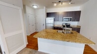 This contemporary 700 square foot apartment in West Chester, PA offers a thoughtful blend of style and functionality. The open-concept layout maximizes the use of space, seamlessly connecting the living room and kitchen areas. Large windows throughout flood the rooms with natural light, creating an airy and inviting atmosphere.

The living areas are adorned with plush wall-to-wall carpeting, providing comfort underfoot. The 140 square foot primary bedroom offers ample space and features the same carpeting and large windows, ensuring a cozy yet bright retreat.

The kitchen is a highlight, boasting modern dark wood cabinetry, gleaming granite countertops, and high-end stainless steel appliances. A central island with a sink adds extra prep space and potential for casual dining. The contrast between the kitchen's hardwood flooring and the carpeted living areas adds visual interest and defines the spaces.

The bathroom continues the modern aesthetic with a spacious vanity, large mirror, and contemporary fixtures. A closet provides additional storage space, complementing the apartment's efficient design.

Overall, this single-floor apartment combines contemporary design elements with practical features, offering a stylish and comfortable living space in a convenient West Chester location.