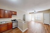 Located at 929 Rockmead Drive in Kingwood, TX, this single-floor, 2-bedroom, 2-bathroom residence offers a functional and comfortable layout with consistent wood-look flooring throughout. The open-concept kitchen and living area serves as the heart of the home, featuring rich cherry wood cabinetry, granite countertops, a peninsula with bar seating, and stainless steel gas range. A black refrigerator and dedicated pantry with built-in shelving add practicality to the kitchen. The living room extends naturally from the kitchen, bathed in natural light from sliding glass doors and fitted with a ceiling fan for year-round comfort. Both bedrooms are well-proportioned, each offering natural light through blinds-covered windows and ceiling fans. The primary bedroom provides a comfortable retreat with ample closet space. The two bathrooms feature wood-look flooring and are equipped with accessibility grab bars, a shower/tub combination, and vanity storage. Five closets throughout the home ensure generous storage. The neutral beige tones and clean white trim present throughout create a cohesive, move-in-ready aesthetic.