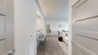 Located in Coeur d'Alene, Idaho, this thoughtfully designed 1-bedroom, 2-bathroom unit offers a modern, open-concept layout with a clean neutral palette and wood-look flooring throughout the main living areas. The living room is bright and welcoming, featuring large sliding glass doors that open to a private balcony and offer views of the surrounding greenery and trees, filling the space with natural light. Adjacent to the living area, the kitchen is well-equipped with rich dark cabinetry, stainless steel appliances including a full-size refrigerator and range, and a light quartz countertop that extends to a breakfast bar with seating — ideal for casual dining. The spacious primary bedroom is carpeted for comfort and includes a window with outdoor views, providing a serene retreat. Two full bathrooms feature dark wood vanities with white quartz counters, large mirrors, and clean tile-look flooring. A dedicated office with carpet flooring and a large window provides a functional flex space for work or relaxation. The in-unit laundry room includes a full-size washer and dryer with overhead shelving for added storage. A walk-in closet completes this well-rounded and efficiently designed home.
