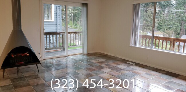Open livingroom with decorative fireplace and wrap around deck - 2002 Floral Hill Dr