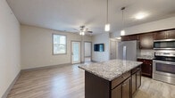 Located on Mortensen Road in Ames, Iowa, this well-appointed 4-bedroom, 4-bathroom unit offers a thoughtfully designed single-floor layout. The open-concept kitchen and living area serves as the heart of the home, featuring rich dark cabinetry, granite countertops, a center island with pendant lighting, and a full suite of stainless steel appliances. Light wood-style flooring runs throughout the main living areas, lending a clean and cohesive aesthetic.

Each of the four bedrooms is generously proportioned and equipped with a ceiling fan. Three bedrooms feature plush carpeting for added comfort, while one offers the same light wood-style flooring found in the main living areas. Multiple bedrooms include windows with blinds that bring in natural light and exterior views. The stylish panel doors and neutral wall tones create a consistent, modern feel throughout.

The four bathrooms are finished with granite-topped dark wood vanities, wood-style tile flooring, and full tub-shower combinations, providing both function and visual appeal. A hallway and closet round out the layout, adding practical storage and circulation space. The entry area features a glass-panel door that allows additional natural light into the home. Overall, the unit presents a clean, contemporary design suited for comfortable everyday living.