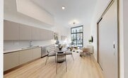 Located at 640 NW 7th Ave in Fort Lauderdale, FL, this modern 1-bedroom, 1-bathroom residence offers a thoughtfully designed open-concept layout with soaring ceilings that amplify the sense of space throughout. Light wood-tone flooring flows seamlessly from the combined kitchen and living area through the hallway and into the bedroom, creating a cohesive and airy aesthetic.

The kitchen is outfitted with stainless steel appliances — including a refrigerator, range, microwave, and dishwasher — complemented by flat-front taupe cabinetry and a clean-lined countertop. A dining area with a round table sits adjacent to the kitchen, making the space ideal for both everyday living and entertaining.

The living room is anchored by dramatic floor-to-ceiling windows with sliding glass door access to a balcony overlooking a lush, landscaped courtyard with palm trees. The bedroom mirrors this feature with its own expansive window, flooding the room with natural light and offering serene outdoor views. Two closets provide ample storage.

The bathroom features a floating vanity with an undermount sink, a soaking tub, and clean white tile finishes. Additional conveniences include in-unit laundry and a utility room, rounding out this well-appointed Fort Lauderdale residence.