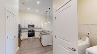Located at 747 N DuPont Hwy in Dover, Delaware, this 2-bedroom, 2-bathroom residence offers a thoughtfully designed single-floor layout with modern finishes throughout. The open-concept kitchen and living area serves as the heart of the home, featuring a striking kitchen with white shaker cabinetry, dark countertops, a subway tile backsplash, stainless steel appliances including a refrigerator, range, microwave, and dishwasher, and pendant lighting above a breakfast bar peninsula. The spacious living room is bathed in natural light and opens directly to a private balcony through sliding glass doors, offering pleasant outdoor views. Both bedrooms are generously sized, featuring large windows, warm-toned walls, and durable hardwood-style flooring. The primary bedroom includes access to a dedicated closet. The two bathrooms are cleanly finished, with one showcasing a white vanity with dark countertop and a large mirror, while the other features accessible grab bars and a walk-in style shower. Light hardwood-style flooring flows consistently through the main living areas and kitchen, while darker flooring accents one of the bedrooms. Two hallways connect the space efficiently, and the overall ambiance is bright, clean, and move-in ready.