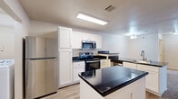 This single-floor residence in Little Rock, Arkansas, offers a practical and well-organized layout across two bedrooms and two bathrooms. The kitchen serves as a central feature, equipped with stainless steel appliances including a refrigerator, range, and over-the-range microwave. White shaker-style cabinetry provides ample storage, while dark granite countertops extend across a peninsula with a built-in sink, creating a natural boundary between the kitchen and the carpeted living area. Recessed panel lighting illuminates the kitchen effectively.

Both bedrooms feature neutral-toned carpet, ceiling fans with light fixtures, and windows that bring in natural light with views of the surrounding community. The primary bedroom includes two closets and a dedicated en-suite bathroom. The en-suite features a white vanity with dark granite countertops, wood-look flooring, and generous counter space. The second bathroom offers a full tub-shower combo with a curved curtain rod and a matching vanity setup. A dedicated laundry area and wood-look flooring in the main entry and wet areas complete this efficiently designed residence.