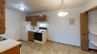 Located at 1300 15th St N in Saint Cloud, Minnesota, this single-floor unit offers a practical and straightforward layout designed for comfortable everyday living. The kitchen is well-equipped with warm oak cabinetry above and below the counters, a stainless steel sink, white appliances including a refrigerator and electric range, and durable tile flooring. A pendant light fixture adds a finished touch to the kitchen area. The living room is generously sized, featuring wall-to-wall carpet, baseboard heating, a wall-mounted air conditioning unit, and a sliding glass door that opens to a balcony, allowing for natural light and outdoor access. The bedroom area continues the carpeted flooring and includes a closet with built-in shelving, providing ample storage. A hallway connects the main living spaces to the bathroom, which features a full tub and shower surround with clean, neutral finishes and chrome fixtures. Throughout the unit, white walls and light-toned surfaces create a bright, neutral backdrop. The textured ceilings and consistent trim work lend a cohesive feel to the space, making it a well-organized and functional home in a convenient Saint Cloud location.