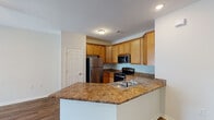 Located at 3282 Turtle Point Dr in Fayetteville, NC, this single-story home presents a thoughtfully designed, open-concept floor plan with consistent wood-style flooring extending throughout the living areas, kitchen, and bedrooms.

The kitchen serves as a central hub of the home, outfitted with warm honey-toned cabinetry extending to the ceiling for ample storage. Stainless steel appliances — including a refrigerator, range, and over-the-range microwave — complement the dark granite-style countertops. A peninsula with a built-in sink and dishwasher provides additional prep space and creates a natural transition into the living area.

The living area is bright and open, benefiting from multiple windows fitted with horizontal blinds and a set of French doors that invite natural light and outdoor views. A ceiling fan with a light fixture adds both comfort and functionality to the space.

The bedrooms are clean and neutrally finished, featuring the same wood-style flooring and six-panel doors. The bathroom includes a wood-toned vanity with a granite-style countertop, a single undermount sink, and a window that brings in natural light. Brushed nickel fixtures carry a cohesive look throughout the space.