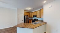 Located at 3282 Turtle Point Dr in Fayetteville, NC, this single-story home presents a thoughtfully designed, open-concept floor plan with consistent wood-style flooring extending throughout the living areas, kitchen, and bedrooms.

The kitchen serves as a central hub of the home, outfitted with warm honey-toned cabinetry extending to the ceiling for ample storage. Stainless steel appliances — including a refrigerator, range, and over-the-range microwave — complement the dark granite-style countertops. A peninsula with a built-in sink and dishwasher provides additional prep space and creates a natural transition into the living area.

The living area is bright and open, benefiting from multiple windows fitted with horizontal blinds and a set of French doors that invite natural light and outdoor views. A ceiling fan with a light fixture adds both comfort and functionality to the space.

The bedrooms are clean and neutrally finished, featuring the same wood-style flooring and six-panel doors. The bathroom includes a wood-toned vanity with a granite-style countertop, a single undermount sink, and a window that brings in natural light. Brushed nickel fixtures carry a cohesive look throughout the space.