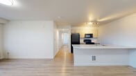 This well-appointed 3-bedroom, 2-bathroom residence in Greeley, Colorado offers a thoughtfully designed single-floor layout with a clean, modern aesthetic. The open-concept living and kitchen area serves as the heart of the home, featuring light wood-style flooring, a peninsula with a white countertop and built-in sink, light wood cabinetry, and black appliances including a refrigerator, range, and microwave. Track lighting illuminates the kitchen, while the adjacent living area is bright and airy, with access to a private balcony through a glass door flanked by large windows. Each of the three bedrooms features plush carpeting, ceiling fans, and large windows with vertical blinds that allow for generous natural light and outdoor views. The primary bedroom offers a comfortable, well-proportioned space with its own dedicated closet. Both bathrooms are finished with light wood-toned vanity cabinetry, white countertops, wood-style tile flooring, and full tub-shower combinations. A dedicated in-unit laundry room houses a full-size washer and dryer with overhead wire shelving for additional storage. A utility room and hallway with multiple closets provide ample organization throughout.