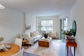 This 580 square foot apartment in London, ON, offers a thoughtfully designed living space on a single floor. The layout includes one bedroom, one bathroom, a kitchen, and a living room, making efficient use of the available area. The primary bedroom, measuring 150 square feet, provides a comfortable retreat.

The living area showcases a bright, open-concept design with large windows and sliding glass doors leading to a balcony, flooding the space with natural light. Neutral-toned walls and wood-look flooring create a modern, airy ambiance. The living room features a plush white sofa, decorative plants, and a wooden coffee table, offering a cozy yet stylish seating area.

The kitchen, while compact, is well-equipped with white cabinetry, a full-size refrigerator, and essential appliances. Tile flooring in the kitchen area provides durability and easy maintenance.

The bathroom boasts a clean, contemporary design with a white vanity, mirror, and toilet. Tile flooring extends throughout, complementing the overall aesthetic. The bedroom continues the apartment's modern theme with a grey upholstered bed, bedside tables, and a large window offering natural light and views.

Throughout the apartment, attention to detail is evident in the baseboard trim, modern light fixtures, and carefully chosen decor, creating a cohesive and inviting living environment perfect for urban dwellers.