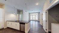 This single-floor residence in Jacksonville, FL (32207) presents a thoughtfully designed open-concept layout anchored by a well-appointed kitchen. The kitchen features white shaker-style cabinetry, dark granite countertops, a large central island with a built-in sink and stainless steel dishwasher, pendant lighting, and a full suite of stainless steel appliances including a refrigerator with ice maker, range, microwave, and additional dishwasher. A dedicated laundry area with a full-size washer and dryer is conveniently situated adjacent to the kitchen.

The open living area flows seamlessly from the kitchen, highlighted by dark hardwood-style flooring, a textured ceiling, and large French doors that invite natural light and outdoor views. The bedrooms are calm and well-proportioned, each featuring ceiling fans, neutral-toned walls, and windows with outdoor courtyard views.

The bathrooms are finished with granite-topped white vanities, framed mirrors, and tub/shower combinations, while a separate bathroom offers a double-sink vanity and a glass-enclosed shower. Storage is well addressed with a spacious walk-in closet outfitted with multi-tier wire shelving throughout.