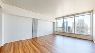 Located on a high floor at 1815–1823 Minor Ave in Seattle's vibrant Denny Triangle neighborhood, this well-appointed unit offers a thoughtfully designed layout comprising a living room, kitchen, and bathroom. Warm hardwood-style flooring runs throughout the space, lending a cohesive and inviting feel.

The open living area is a highlight, featuring expansive floor-to-ceiling windows that frame sweeping views of the Seattle skyline, allowing abundant natural light to fill the room and creating a bright, airy atmosphere.

The galley-style kitchen is outfitted with modern dark cabinetry, sleek quartz countertops, a tile backsplash, and a full suite of stainless steel appliances including a gas range, microwave, dishwasher, and undermount sink. Under-cabinet lighting adds both functionality and a polished finish.

The bathroom features clean, contemporary design with large-format white wall tiles, a full soaking tub, and tile flooring, offering a calm and functional space.

The unit's clean lines, neutral palette, and high-rise positioning combine to create a sophisticated urban living environment in the heart of Seattle.