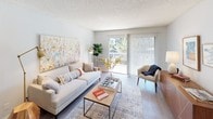 This single-story unit presents a thoughtfully designed open-concept layout with distinct living, dining, and kitchen zones that flow seamlessly together. The living area is bright and inviting, featuring wood-look flooring, a textured ceiling, and a sliding glass door that opens onto a balcony, offering natural light and outdoor views. A dedicated dining area adjacent to the living space includes a ceiling fan with integrated lighting, adding to the room's functionality.

The kitchen is efficiently arranged in a galley configuration, appointed with white cabinetry, a gray quartz countertop, and stainless steel appliances including a refrigerator, range, and microwave. A peninsula with a breakfast bar provides additional seating and workspace, making the kitchen both practical and social.

The unit includes two bedrooms, each finished with wood-look flooring, neutral wall tones, and windows that allow natural light to filter in. One bedroom features a mirrored closet, enhancing the sense of space. The bathroom is clean and well-appointed, offering a combined tub and shower, a single undermount sink set into a quartz vanity, and white cabinetry for storage. Throughout, the unit maintains a cohesive, contemporary aesthetic.
