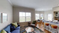 Located at 1802 Ennis Joslin Rd in Corpus Christi, Texas, this single-story residence offers a well-designed layout that balances comfort and functionality throughout. The living area features crown molding, warm hardwood-style flooring, and large windows dressed with white blinds that invite generous natural light and outdoor views of the surrounding greenery. A seamless transition connects the living space to a bright dining nook anchored by a glass-top table and surrounded by windows on multiple sides, with direct access to an exterior door.

The galley-style kitchen is outfitted with white cabinetry, light countertops, stainless steel appliances, and a herringbone tile backsplash. A dedicated in-unit laundry area is conveniently accessible just off the kitchen. Multiple bedrooms provide versatile living options, each finished with the same hardwood-style flooring, neutral wall tones, ceiling fans, and windows that bring in natural light. The bedrooms offer a calm, restful ambiance suited for a variety of uses.

The bathroom is clean and functional, featuring wood-style flooring and a shower-tub combination. Consistent neutral tones and clean white trim throughout the home create a cohesive, inviting aesthetic that is both modern and livable.