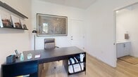 Located in San Pedro, CA, this contemporary multi-story home spans three floors and offers a well-appointed layout designed for both comfort and functionality. The entry level provides a compact but purposeful footprint, leading to the main living floor above. The heart of the home features an open-concept living, dining, and kitchen area bathed in natural light from large windows that frame neighborhood views. The living room showcases light hardwood flooring, recessed lighting, and a bold blue sofa that anchors the space. The sleek kitchen is outfitted with white cabinetry, quartz countertops, stainless steel appliances, and a clean subway tile backsplash. The adjacent dining area features soft gray walls, a light wood table, and contemporary artwork. Two dedicated office spaces provide flexibility for remote work or study, each featuring light hardwood floors, ceiling fans, and generous wall art. The seven bathrooms are finished with modern vanities, wood-look flooring, and clean white fixtures. Both bedrooms offer a calm retreat, with the primary bedroom boasting soaring ceilings, a large picture window with neighborhood views, and ample space. The second bedroom features soft tones and closet storage. Stairways connect each floor seamlessly throughout this thoughtfully designed home.