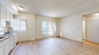 Located at 1332 S Hope St, Unit 205 in Los Angeles, CA, this studio unit offers a practical and well-organized layout across a single floor. Light wood laminate flooring runs throughout the entire space, providing a clean and cohesive aesthetic. The combined kitchen and living area serves as the heart of the unit, featuring white cabinetry that extends to the ceiling for ample storage, a full suite of white appliances including a refrigerator and range, a double-basin sink with a classic faucet, and dark countertops that offer a subtle contrast. The living area benefits from multiple windows dressed with vertical blinds, allowing natural light to brighten the space. A textured popcorn ceiling is consistent throughout the unit. The hallway connects the main living area to the bathroom, which is outfitted with a full bathtub and shower combination, a small window for natural ventilation, a wall-mounted vanity with under-sink storage, and a toilet. Two closets provide convenient built-in storage solutions. The entry area includes additional utility features, ensuring functional use of every corner of this compact yet efficiently designed Los Angeles studio.