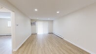 This 2-bedroom, 1-bathroom unit at 950 Washington St in Middletown, CT offers a thoughtfully organized single-floor layout. Light-toned hardwood flooring runs consistently throughout, contributing to a clean, cohesive aesthetic across all rooms.

The living room is a generously proportioned open space featuring recessed lighting, a wall-mounted air conditioning unit, vertical blinds over a sliding door, and baseboard heating. Neutral walls create a bright, versatile environment.

The kitchen is well-appointed with white cabinetry, a decorative tile backsplash, white quartz-style countertops, and stainless steel appliances including a refrigerator, electric range, and dishwasher. A peninsula provides additional counter space and separates the kitchen from the living area.

Both bedrooms feature light hardwood flooring, baseboard heating, and neutral walls. The primary bedroom includes a full-width double closet and a window with blinds. The second bedroom is compact yet functional, with recessed lighting and baseboard heating.

The bathroom features large-format beige tile surrounding the tub-shower combination, a wood-toned vanity with a white countertop, and a window for natural light and ventilation.