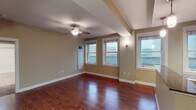 Located at 127 S Roach St in the heart of downtown Jackson, Mississippi, this single-floor unit offers a well-designed layout that balances comfort and functionality. The entryway welcomes you with rich, dark hardwood flooring that extends throughout the main living areas, complemented by warm neutral wall tones and structural beam details that add architectural character to the space.

The open-concept living area is generously proportioned, featuring multiple windows that frame views of the surrounding cityscape, filling the room with natural light. A ceiling fan adds to the comfort of the space. The living area connects seamlessly to the kitchen, which is outfitted with warm wood cabinetry, granite countertops with a dark tile backsplash, stainless steel appliances including a refrigerator, oven, and built-in microwave, and a breakfast bar with stylish pendant lighting overhead. Tile flooring in the kitchen complements the overall design.

The bedrooms are carpeted for comfort and each feature ceiling fans and windows with city views, providing a quiet retreat. The bathroom is clean and functional, appointed with white tile surrounding a full soaking tub and shower combination, tile flooring, and a vanity with a granite countertop. Throughout the unit, thoughtful finishes and an abundance of natural light create a bright, livable urban environment.