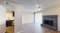 This two-story home offers a thoughtfully organized layout spread across two floors, with two bedrooms, four bathrooms, and four closets providing ample storage throughout. The main floor centers around a bright, open living area distinguished by a classic brick fireplace, hardwood-style flooring, and a ceiling fan overhead. Large sliding glass doors invite natural light and connect the living space to the outdoors. The kitchen is designed as a galley-style space featuring dark gray cabinetry, white quartz-style countertops, a white subway tile backsplash, and a full suite of stainless steel appliances including a refrigerator, range, and over-the-range microwave. The bathrooms are consistently finished with navy blue cabinetry, wood-look flooring, white quartz vanity tops, and tub-shower combinations with curved curtain rods. A staircase connects the two floors, leading to the upper level where the bedrooms are located. Both bedrooms are carpeted and feature ceiling fans and windows with blinds that allow for natural light. One bedroom includes a built-in window seat, adding a functional architectural detail. The textured ceilings are present throughout, contributing to the home's warm and lived-in character.
