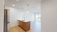 Located in Blair, Nebraska, this single-floor unit offers a thoughtfully designed layout that maximizes every square foot of its compact footprint. Light wood-style flooring runs continuously throughout, creating a cohesive and warm aesthetic across all rooms.

The kitchen is a standout feature, anchored by a peninsula-style island with a white countertop, undermount double sink, and brushed nickel faucet. Warm wood cabinetry lines the walls and base of the island, complemented by stainless steel appliances including a refrigerator, range, and built-in microwave. Stylish pendant lights hang above the island, adding a modern touch. Recessed lighting keeps the space well-illuminated, while a sliding glass door leads to a private balcony, inviting natural light into the open living area.

The bathroom is clean and functional, featuring a full tub-shower combination with a curved rod and tiled surround, a wood-base vanity with a white countertop, and brushed nickel fixtures and grab bars throughout.

A dedicated walk-in closet provides practical storage, outfitted with wire shelving systems along the walls and ceiling for organized use of the space.

The overall ambiance is modern, clean, and light-filled, with a neutral white and warm wood palette that makes the unit feel open and inviting.