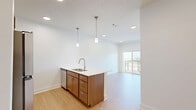 Located in Blair, Nebraska, this single-floor unit offers a thoughtfully designed layout that maximizes every square foot of its compact footprint. Light wood-style flooring runs continuously throughout, creating a cohesive and warm aesthetic across all rooms.

The kitchen is a standout feature, anchored by a peninsula-style island with a white countertop, undermount double sink, and brushed nickel faucet. Warm wood cabinetry lines the walls and base of the island, complemented by stainless steel appliances including a refrigerator, range, and built-in microwave. Stylish pendant lights hang above the island, adding a modern touch. Recessed lighting keeps the space well-illuminated, while a sliding glass door leads to a private balcony, inviting natural light into the open living area.

The bathroom is clean and functional, featuring a full tub-shower combination with a curved rod and tiled surround, a wood-base vanity with a white countertop, and brushed nickel fixtures and grab bars throughout.

A dedicated walk-in closet provides practical storage, outfitted with wire shelving systems along the walls and ceiling for organized use of the space.

The overall ambiance is modern, clean, and light-filled, with a neutral white and warm wood palette that makes the unit feel open and inviting.