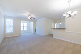 This single-floor residence offers a thoughtfully designed open-concept layout that connects the living, dining, and kitchen areas into one cohesive, light-filled space. The expansive living room features plush wall-to-wall carpeting, crown molding, and a ceiling fan with light fixture, while large windows with blinds invite generous natural light throughout. An elegant chandelier marks the dining area, which opens seamlessly to the kitchen via a raised peninsula counter topped with rich granite surfaces — ideal for casual dining or entertaining.

The kitchen is well-appointed with warm wood cabinetry reaching to the ceiling, granite countertops, tile flooring, and black appliances including a refrigerator, range, and built-in microwave. A pendant light above the peninsula adds a refined touch.

The bedrooms are carpeted and generously proportioned, offering ample space and closet storage, including a room with a dedicated closet fitted with wire shelving. Natural light flows through multiple windows in the secondary bedroom areas, enhancing the airy feel of the space.

The bathroom features tile flooring, a warm wood vanity with granite countertops, a large mirror, and a soaking tub with shower combination. Throughout the residence, neutral warm tones and clean white trim create a cohesive and welcoming ambiance.