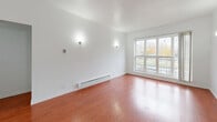 Located at 4901 South Drexel Boulevard in Chicago's Woodlawn neighborhood, this one-bedroom, one-bathroom unit offers a well-organized single-floor layout. The entrance leads into a hallway that connects the main living areas, providing a clear and functional flow throughout the space.

The living room is bright and open, featuring rich hardwood flooring, white walls, and a large window that fills the room with natural light and offers outdoor views. Wall-mounted sconces and a baseboard heating system are present throughout.

The kitchen is laid out in a galley style with light ceramic tile flooring, warm wood cabinetry, dark countertops, a range, and a full-size refrigerator. A window brings in additional natural light, and the electrical panel is conveniently accessible within the space.

The spacious bedroom is a standout feature, showcasing a distinctive curved wall lined with three large windows that frame outdoor greenery and neighborhood views. Plush carpet and a dedicated closet provide comfort and storage.

The bathroom includes a full tub-shower combination with floor-to-ceiling neutral tile surround, a white vanity, and tile flooring. Two closets serve the unit, offering practical storage solutions. The overall aesthetic is clean and functional, with a neutral color palette throughout.