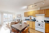 This efficiently designed 1-bedroom, 1-bathroom unit offers a thoughtful open-concept layout that seamlessly connects the living, dining, and kitchen areas into a cohesive and functional living space. Light hardwood-style flooring runs throughout, lending warmth and visual continuity across every room.

The kitchen is well-appointed with abundant light wood cabinetry, dark countertops, a double-basin sink, a full suite of white appliances including a refrigerator, electric range, and dishwasher, and track lighting overhead that provides excellent task illumination. The adjacent dining area comfortably accommodates a full dining table, while the living room benefits from large sliding glass doors that open onto a private balcony, filling the space with natural light and providing outdoor access.

The bedroom is a quiet, private retreat with clean white walls, hardwood-style flooring, and a dedicated closet with louvered doors. In total, the unit features three closets, offering ample storage throughout. The full bathroom is finished with white tile, a tub/shower combination, a single-sink vanity with wood cabinetry, and a large mirror. A hallway connects the main living area to the bedroom and bathroom, adding a sense of separation and privacy to the overall floor plan.