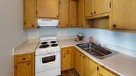 Located at 140 N Main St in downtown Lima, Ohio, this single-floor unit offers a straightforward and functional layout. The 3D floor plan reveals a compact yet practical arrangement of rooms, with distinct areas for living, cooking, and bathing connected by an efficient flow.

The kitchen is appointed with warm oak cabinetry providing ample upper and lower storage, light-toned countertops, a stainless steel sink, a white coil-burner electric range with overhead ventilation, and a stainless steel refrigerator. Wood-look flooring grounds the space and transitions cleanly from the kitchen into the adjoining areas.

The main living area features neutral carpet flooring, white walls, and a textured ceiling. Two windows allow natural light to filter in, offering views of the surrounding downtown streetscape. A wall-mounted air conditioning unit and baseboard heating provide year-round climate control throughout the space.

The bathroom includes wood-look flooring consistent with the kitchen, a full tub and shower combination, and a toilet, all within a clean, simply finished space.

Overall, the unit presents a clean, functional environment in a central downtown Lima location.