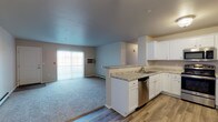 This single-floor unit offers a thoughtfully designed open-concept layout that seamlessly connects the kitchen and living area. The kitchen is well-equipped with stainless steel appliances, including a range, microwave, dishwasher, and refrigerator, all complemented by crisp white cabinetry, granite-style countertops, and durable wood-look flooring. A peninsula counter separates the kitchen from the carpeted living area, which is brightened by a large sliding glass door and a ceiling fan overhead.

The unit includes two bedrooms, each finished with plush carpeting, ceiling fans, and windows fitted with blinds that allow for natural light and privacy. Baseboard heating is present throughout, ensuring year-round comfort.

Two bathrooms serve the unit — one featuring a walk-in shower, white vanity with granite-style countertop, and wood-look flooring, and a second with a similarly styled vanity, lighted mirror, and additional storage. Both bathrooms maintain a clean, cohesive aesthetic.

A dedicated laundry room houses a full-size top-loading washer and dryer, adding everyday convenience. The consistent use of white trim, neutral tones, and modern finishes throughout gives the space a clean, functional, and move-in-ready character.