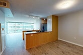 Located at 9739 Woods Dr in Skokie, IL, this single-floor residence offers 2 bedrooms, 3 bathrooms, and a thoughtfully designed layout that maximizes both functionality and comfort. The living and dining areas are bathed in natural light from expansive floor-to-ceiling windows that frame open outdoor views, and light wood-tone flooring runs throughout these common spaces, enhancing the bright, airy ambiance. The kitchen is a standout feature, equipped with warm wood cabinetry, granite countertops, stainless steel appliances including a gas cooktop, double wall oven, dishwasher, and French door refrigerator, plus track lighting overhead. A peninsula-style counter connects the kitchen seamlessly to the living and dining areas. The spacious primary bedroom, finished with plush carpeting, includes mirrored sliding closet doors and access to an outdoor balcony. The second bedroom is similarly carpeted with ample closet space. Three full bathrooms serve the residence, one of which features tile surround, a soaking tub, and wood vanity cabinetry. A dedicated laundry room and four closets — including a large walk-in with wire shelving — provide exceptional storage. A connecting hallway ties all spaces together efficiently.