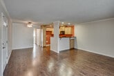 Located at 2828 W Ball Rd in Anaheim, California, this single-story residence offers a well-organized layout with a thoughtful blend of materials and finishes throughout. The living area greets visitors with rich, dark hardwood flooring, crown molding, and a large sliding glass door fitted with vertical blinds that allows generous natural light and views of the surrounding greenery. A ceiling fan adds to the comfort of the space.

The kitchen is a standout feature, showcasing light maple cabinetry that reaches toward the ceiling, bold red accent walls, and striking dark granite countertops. Black appliances, including a range, microwave, and dishwasher, complement the dramatic color palette. Recessed lighting illuminates the workspace, and a breakfast bar peninsula connects the kitchen to the main living area, making it ideal for casual dining or entertaining.

The bedrooms are carpeted for warmth and comfort, each equipped with ceiling fans. The rooms offer ample wall space and access to closets, with natural light filtering in through windows and sliding doors.

The bathrooms are cleanly appointed with hardwood-style flooring, sliding glass shower enclosures with brushed nickel hardware, and granite-topped vanities, providing a cohesive and functional finish throughout the home.