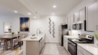 Located at 380 Topwater Dr in Clayton, NC, this single-floor, 2-bedroom, 2-bathroom residence offers a thoughtfully designed layout with modern finishes throughout. The open-concept kitchen and living area serves as the heart of the home, where the kitchen impresses with gray shaker-style cabinetry, a white subway tile backsplash, stainless steel appliances, and a striking granite island with an undermount sink. Wood-look flooring flows through the main living areas, while crown molding and recessed lighting add a polished touch. The living room is bright and welcoming, with large windows allowing natural light to fill the space and a door providing outdoor access. Both bedrooms are generously proportioned, featuring plush carpet, ceiling fans, and ample natural light. The spacious primary bedroom includes a large walk-in closet with wire shelving. Each bathroom is well-appointed, with one featuring a full tub-shower combination. Two dedicated laundry areas add everyday convenience. An entry closet near the front door provides additional storage. The hallway connects each room efficiently, contributing to the home's practical and comfortable flow throughout.