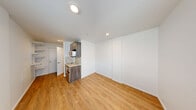 Located at 16210 NE 80th St in Redmond, WA, this efficiently designed studio unit makes smart use of every square foot across a single floor. The open living area features warm hardwood-style flooring and crisp white walls, with windows fitted with blinds that allow natural light to filter in and offer views of the surrounding neighborhood.

The kitchenette is thoughtfully appointed with dark wood cabinetry, a marble-style stone countertop and backsplash, a stainless steel sink, an over-the-range microwave, and a compact under-counter refrigerator — providing essential cooking and storage functionality in a streamlined layout. Adjacent to the kitchen, a dedicated built-in shelving unit with adjustable white shelves offers versatile storage and organizational options.

The bathroom includes a clean, all-white walk-in shower stall with a chrome showerhead and lever-style fixtures, maintaining a simple and functional aesthetic. Throughout the unit, the consistent use of light tones, natural-finish flooring, and recessed lighting contributes to a bright and cohesive atmosphere. This unit is well-suited for those seeking a practical, low-maintenance space in a convenient Redmond location.