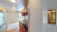 This single-floor residence offers a practical and comfortable layout designed to maximize everyday livability. The kitchen is efficiently arranged with warm-toned wooden cabinetry providing ample upper and lower storage, granite-style laminate countertops, a stainless steel double-basin sink, a black electric coil range with an overhead ventilation hood, and hardwood-style flooring. A window above the sink allows natural light into the cooking area, which opens toward the adjacent living space.

The spacious living room is finished with plush neutral carpet and features a textured ceiling throughout. A full-width sliding glass door provides direct access to a private outdoor balcony with a wooden railing, allowing natural light to fill the room and offering outdoor views of surrounding trees.

The bedrooms are generously sized, each carpeted and finished with the same neutral tones. Both rooms feature windows that bring in natural light and exterior views, with one room benefiting from a corner window configuration that enhances the sense of openness.

The bathroom includes a full soaking tub enclosed by a clean white surround with a built-in shelf, complemented by chrome fixtures. Throughout the unit, textured ceilings, HVAC vents, and neutral wall tones create a cohesive, understated aesthetic.