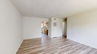 This single-story home in Memphis, Tennessee offers a thoughtfully arranged layout featuring four bedrooms, two full bathrooms, and a generous amount of closet space across five dedicated storage areas. The living room greets residents with light-toned luxury vinyl plank flooring, neutral white walls, and a large window dressed with vertical blinds that allows natural light to fill the space. The kitchen is well-equipped with warm honey-toned wood cabinetry extending along the full wall, providing abundant storage. It features a coil electric range, a double-basin sink, a dishwasher, and light-colored countertops — a practical and functional cooking space. The four bedrooms are finished with wall-to-wall carpet and maintain a clean, neutral palette, offering comfortable and quiet retreats. The primary bedroom is notably spacious, providing room for substantial furnishings. Both bathrooms are finished consistently with white subway tile surrounding full tub-shower combinations, paired with wood-toned vanities and white countertops. A dedicated laundry area with hookups is also present within the unit. A connecting hallway ties the layout together efficiently, and the overall design emphasizes a clean, move-in-ready aesthetic throughout.