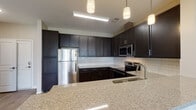 Located at 1 Bluebill Dr in Pembroke, NC, this single-floor residence offers a thoughtfully designed layout with modern finishes throughout. The kitchen is a standout feature, showcasing rich dark cabinetry paired with light granite countertops, a classic white subway tile backsplash, stainless steel appliances including a refrigerator, microwave, and range, and pendant lighting that adds a contemporary touch. Ample counter and storage space make this kitchen as functional as it is attractive.

The open living area features light-toned luxury vinyl plank flooring, neutral wall colors, and a ceiling fan, creating a bright and airy atmosphere. Bedrooms are carpeted for comfort and include windows with blinds that allow natural light while maintaining privacy.

The primary bathroom is well-appointed with a dark-stained vanity, granite countertop, a soaking tub with shower, and direct access to a spacious walk-in closet outfitted with wire shelving systems for organized storage. A secondary bathroom mirrors the same design aesthetic with a dark vanity, granite countertop, and light wood-look flooring. The home's consistent use of neutral tones and quality materials creates a cohesive, modern living environment throughout.