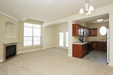 This single-floor residence offers a well-organized layout with a cohesive design throughout. The kitchen is appointed with rich, dark wood cabinetry, light countertops, and a full suite of stainless steel appliances, including an electric range, built-in microwave, and dishwasher. A distinctive oval window above the sink provides a charming architectural detail while bringing in natural light. Light-toned flooring completes the practical yet attractive space.

The living area is generously sized, featuring warm neutral-toned carpet, crown molding, and a brick-surround fireplace with a white mantel as a focal point. A built-in arched niche above the fireplace adds character, while a large window allows natural light to fill the room. An adjacent dining area, accessed through a decorative arched opening with column detail, is highlighted by an elegant chandelier. French doors lead to an exterior access point.

The bedrooms are carpeted and finished in soft neutral tones, each featuring windows with blinds and ceiling fans for comfort. The bathrooms are consistent in design, offering dark wood vanity cabinetry, light countertops, mirrored storage, and wood-look tile flooring, providing a clean and functional finish throughout the residence.