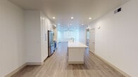 Located in Goleta, California, this single-floor residence at 6720 Calle Koral offers a thoughtfully designed layout with modern finishes throughout. The open-concept kitchen and living area serves as the heart of the home, anchored by a striking white quartz waterfall island with a gold-toned faucet. Crisp white shaker cabinetry with brushed hardware lines the kitchen walls, complemented by stainless steel appliances including a professional-style range and refrigerator. Recessed lighting illuminates the space, which flows seamlessly across light-toned wood-look flooring. The living and dining areas extend from the kitchen, bathed in natural light from multiple windows fitted with horizontal blinds. Ceiling fans are featured in several rooms, enhancing comfort throughout. The bedrooms offer plush carpeting and generous natural light, while the bathrooms are finished to a high standard — one featuring a dual-sink vanity with a quartz countertop, brushed nickel fixtures, and a full-width mirror, and another with a single-sink vanity and wood-look tile flooring. Clean white walls and consistent trim details create a bright, cohesive aesthetic across all spaces, reflecting a fresh, move-in-ready condition.