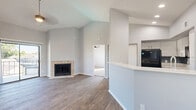 Located at 9988 Windmill Lakes Blvd in Houston, TX, this two-bedroom, two-bathroom single-floor home offers a well-designed layout with notable architectural character throughout. Soaring vaulted ceilings in the living room create an open, airy ambiance, anchored by a tile-surround wood-burning fireplace that serves as a focal point. Wood-look flooring flows through the living, dining, and kitchen areas, adding warmth and continuity to the shared spaces.

The kitchen is outfitted with white cabinetry, a grey subway tile backsplash, black appliances including a refrigerator, range, and over-the-range microwave, and a single-basin sink — all combining for a clean, functional workspace. A breakfast bar peninsula connects the kitchen to the living area.

Sliding glass doors off the living room lead to a private balcony with outdoor views. Both bedrooms feature plush carpeting and vaulted ceilings that enhance the sense of space. The primary bedroom benefits from multiple windows that invite abundant natural light and includes a ceiling fan. The second bedroom also features a window with natural light.

Both bathrooms are appointed with white vanity cabinetry, quartz-style countertops, and wood-look tile flooring. The full bathroom includes a tub-shower combination. Additional highlights include three closets, a dedicated laundry area, and a hallway connecting the home's rooms efficiently.