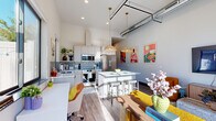 Located at 1481 Blazing Star Blvd in Eau Claire, WI, this thoughtfully designed one-bedroom, one-bathroom unit offers an efficient and stylish layout across a single floor. The open-concept living and kitchen area is anchored by soaring ceilings with exposed ductwork, giving the space an industrial-chic character. Warm wood-look flooring runs throughout, complemented by abundant natural light streaming through large black-framed windows.

The kitchen is a standout, featuring crisp white cabinetry, a grey tile backsplash, stainless steel appliances including a full-size refrigerator, range, microwave, and dishwasher, along with a central island with seating — ideal for both cooking and entertaining. Pendant lighting with woven rattan shades adds warmth to the space.

The bedroom is generously proportioned with tall ceilings, large windows offering outdoor views, and direct access to a walk-in closet outfitted with built-in shelving and double hanging rods. The bathroom includes a walk-in shower, a floating vanity with a backlit mirror, and wood-look tile flooring. A dedicated laundry room with a full-size washer and dryer completes this well-appointed unit.