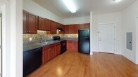 Located at 255 E Grand Ave in Rahway, New Jersey, this single-floor residence offers a thoughtfully designed layout that balances functionality with comfort. The open-concept living and dining area is anchored by warm hardwood flooring and filled with natural light, creating an inviting, airy atmosphere. A seamless transition leads into the kitchen, which is equipped with rich cherry wood cabinetry, dark granite-style countertops, a mosaic tile backsplash, and a full suite of black appliances including a range, dishwasher, and refrigerator — all set atop matching hardwood floors.

The bedrooms are carpeted for comfort and feature large windows with blinds that frame pleasant outdoor views of mature trees, along with individual wall-unit HVAC systems for personalized climate control. The primary bathroom is well-appointed with a cherry wood vanity, tile flooring, and a glass-enclosed walk-in shower with decorative tile accents. A second bathroom offers a matching vanity with ample storage and a tub-shower combination. A dedicated walk-in closet provides generous storage with built-in wire shelving and a freestanding shelving unit. Throughout the space, neutral wall tones and clean finishes contribute to a cohesive, move-in-ready aesthetic.