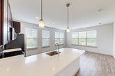 Located at 50 Woodview Way in Franklin, MA, this well-appointed unit offers a thoughtfully designed single-floor layout with three bedrooms, two bathrooms, and a dedicated kitchen. The kitchen stands out with rich dark wood cabinetry, stainless steel appliances including a refrigerator, electric range, and built-in microwave, complemented by light countertops and wood-look vinyl flooring that extends into the adjacent living area. The open living space is bright and airy, featuring large windows with slatted blinds that frame lush outdoor greenery and allow abundant natural light throughout.

The primary bedroom is generously sized, offering plush carpeting and a large window with pleasant outdoor views. The two additional bedrooms are equally comfortable, each featuring soft carpet flooring, neutral walls, and windows overlooking the surrounding landscape. Two dedicated closets provide practical storage solutions throughout the unit.

The two bathrooms are finished with clean, modern details. One features a full tub-shower combination clad in classic white subway tile with chrome fixtures, while the second includes a dark wood vanity with a white countertop, a framed mirror, and wood-look flooring. The consistent use of neutral tones and quality finishes throughout creates a cohesive and move-in-ready living environment.